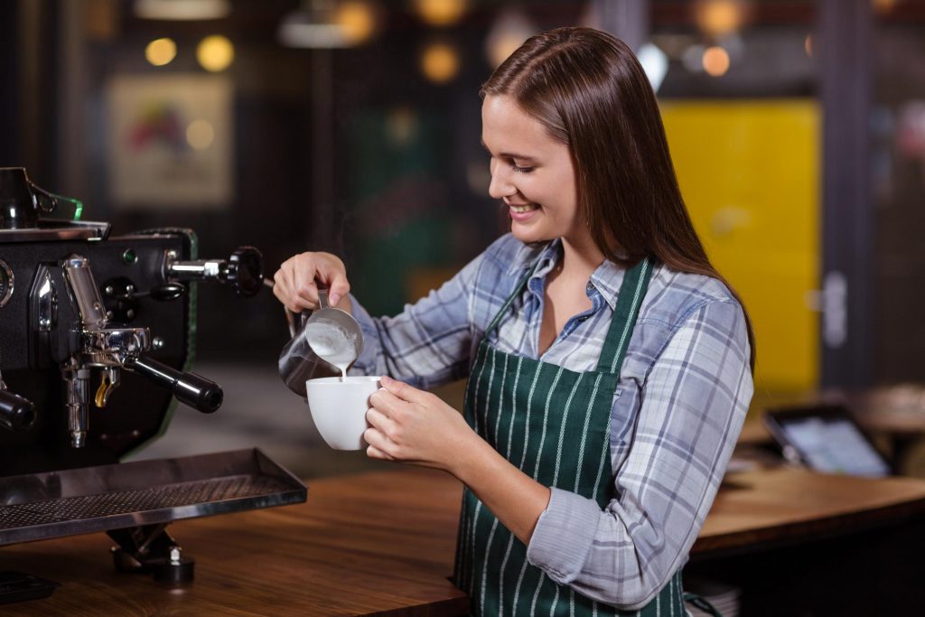 A lady mixing the milk into the coffe